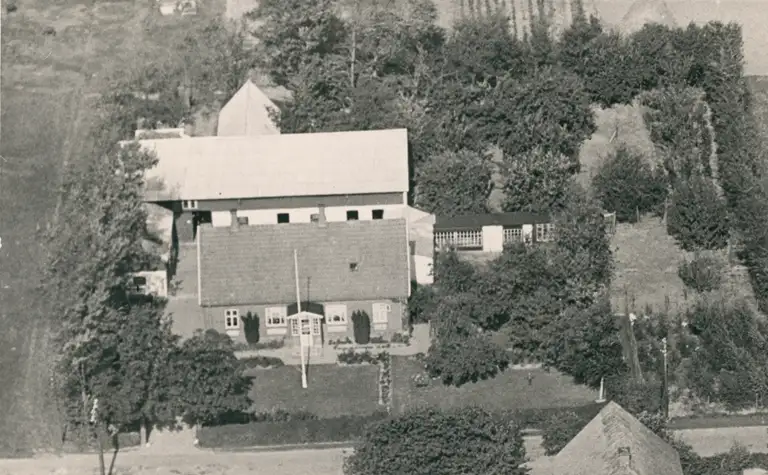 Luftfoto af Frændekilde, Ørby, ejet af Hans Peter Pedersen. I forgrunden stuehus, stalden bagved, til højre evt. et drivhus. Cirka 1950. Fotograf ukendt.