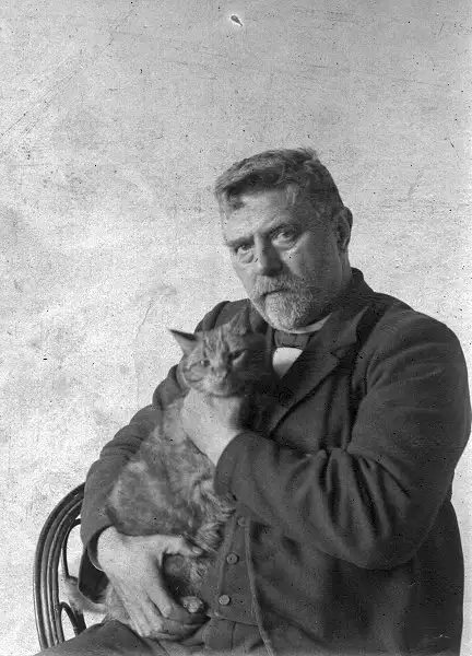 Pastor Peder med sin store kat, der efter sigende var rød og vejede 8 kg. Fotograferet i 1910.