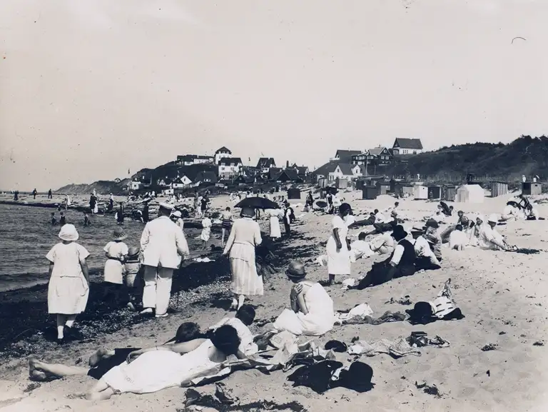 Tisvildelejes offentlige strand med glade badegæster og badehuse i baggrunden, ca. 1910.
