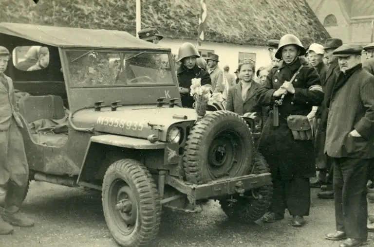 Poul Larsen i sin frihedskæmperuniform foran Gilleleje Kro på Vestergade i maj 1945. Han står ved siden af en engelsk jeep, der ankom i dagene efter befrielsen.